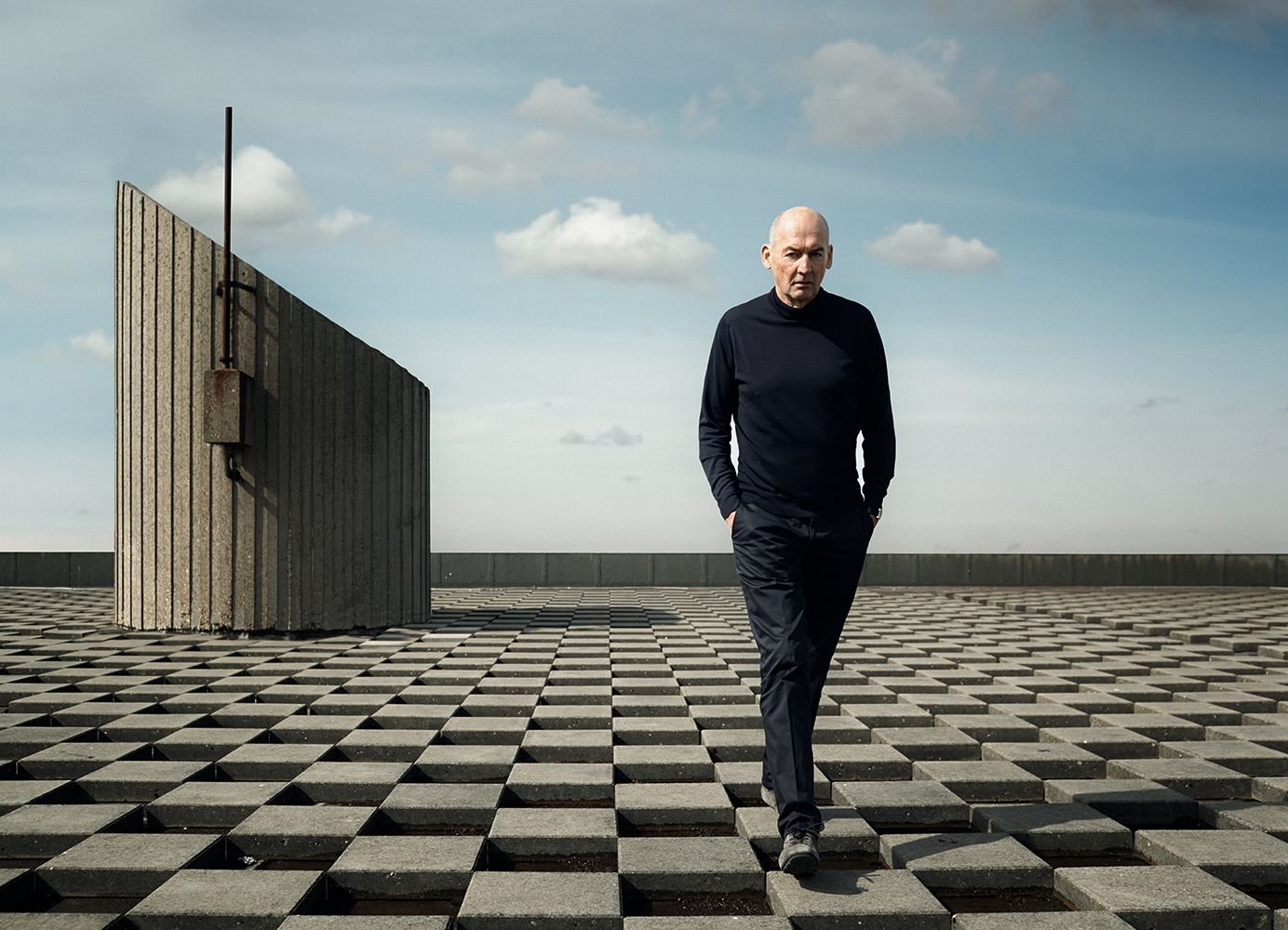 Rem Koolhaas walking on a chest field.